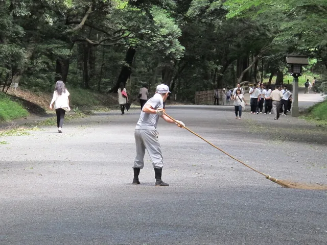 Kerti munkás gereblyével tisztítja és gondozza a park sétányát